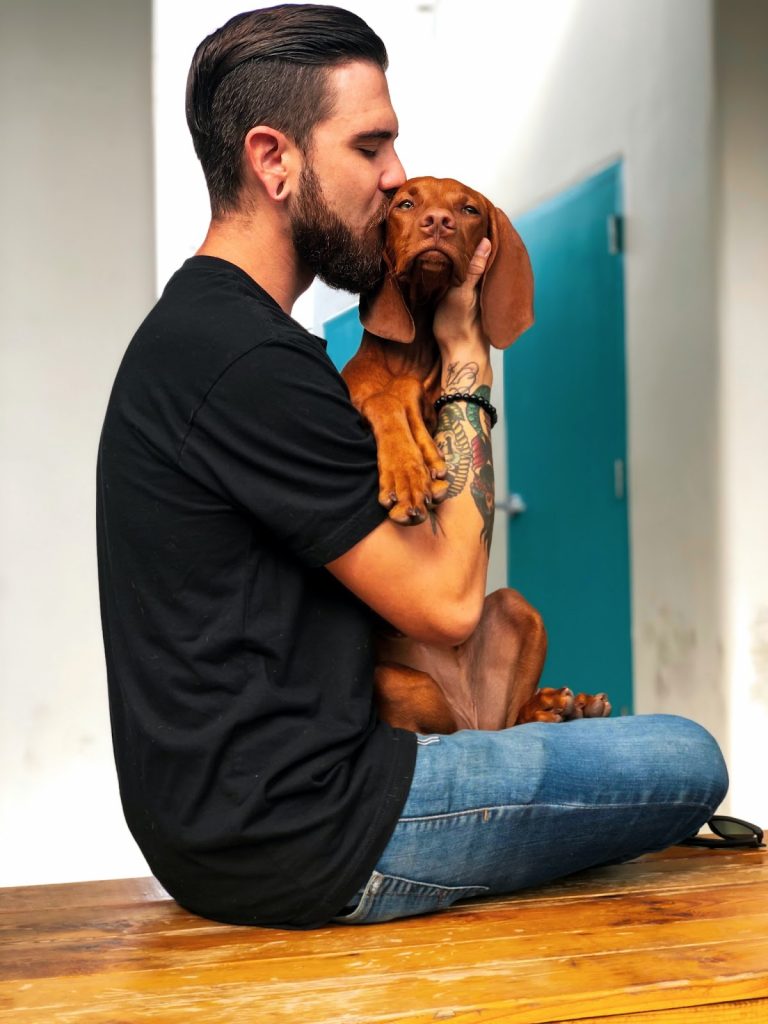 Photo of a man kissing his dog