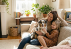 a woman and daughter sitting on a couch hugging their dog